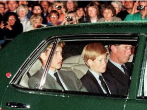 Harry sits between his father and brother in the back of a car, looking shell shocked during his mother's funeral.